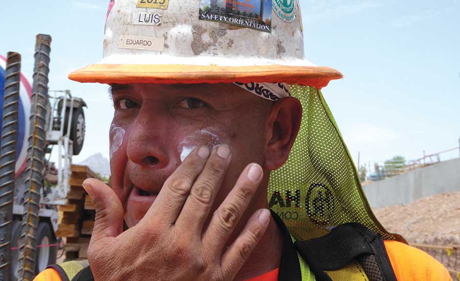 Construction tradesworker applies sunscreen
