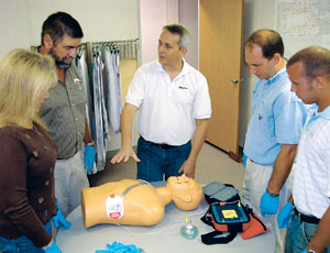 Moss safety manager Gerard (center) demonstrates defibrillator device operation to other contractor employees. The firm has deployed the devices at U.S. and Caribbean jobsites.