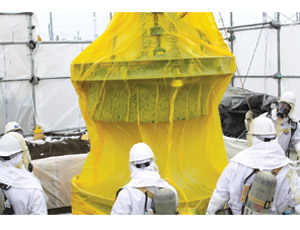 Crew lifts an underground concrete waste tank’s plug—wrapped in protective plastic to avoid contamination spread during operation—to install a robotic waste removal arm. 
