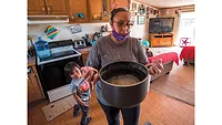 woman in a kitchen with a pot of water woman in a kitchen with a pot of water