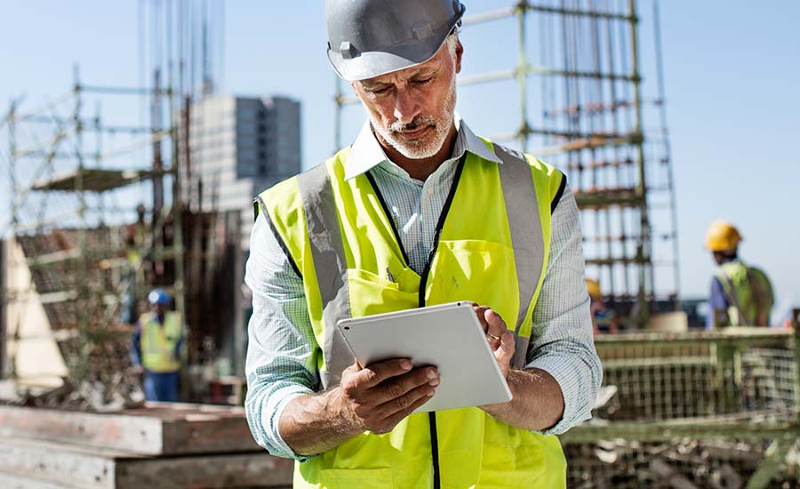 a man in a yellow construction vest looking at a tablet
