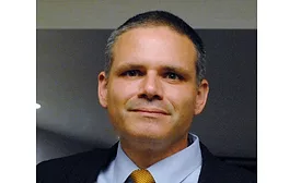 Headshot of Matthew Tejada wearing suit jacket, light blue shirt and gold tie