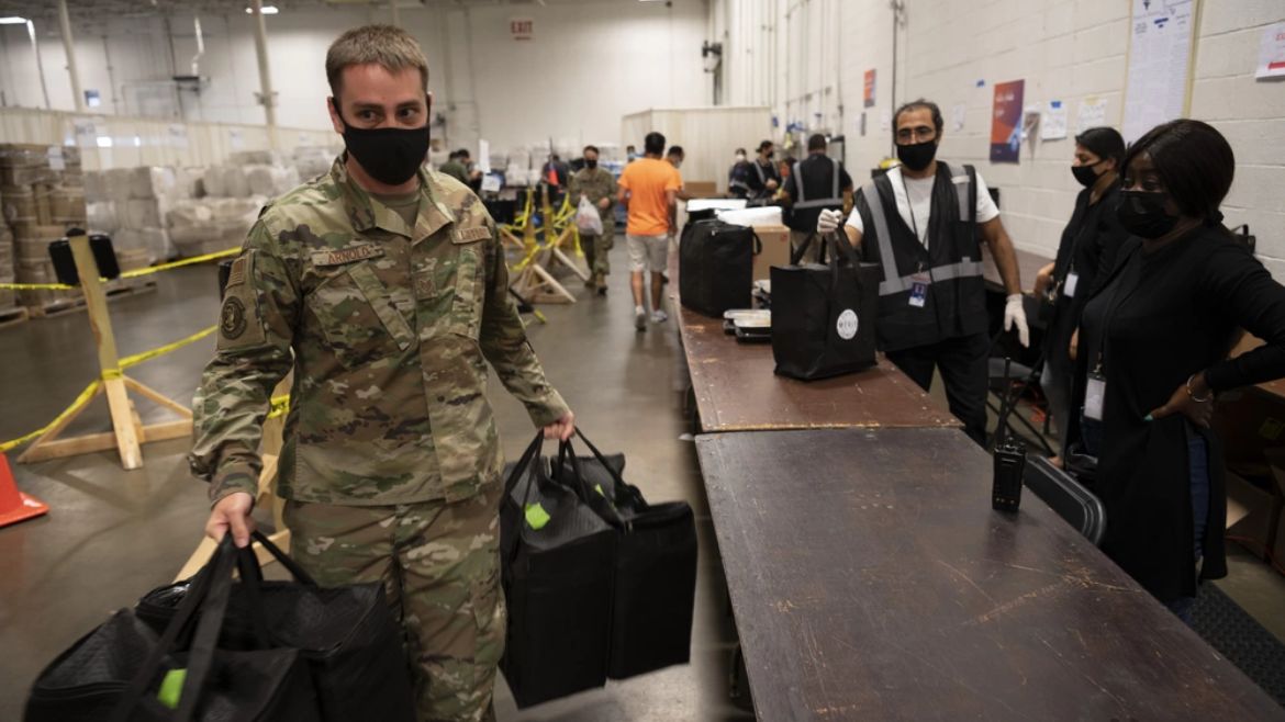 An Air Force staff sergeant carries bags of food for Afghan evacuees inside Dulles Expo Center