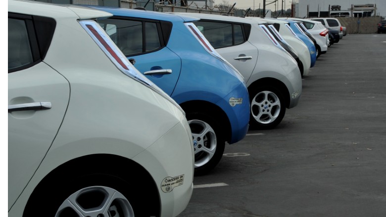 The rear of a row of electric vehicles is shown, in alternating blue and white colors.