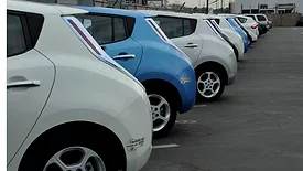 The rear of a row of electric vehicles is shown, in alternating blue and white colors.