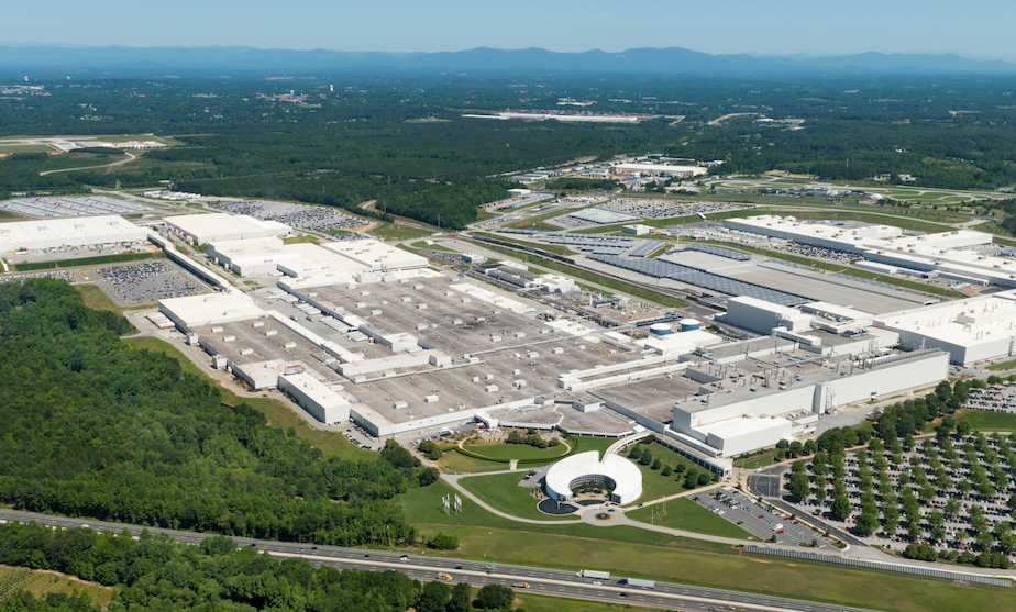 Aerial view of the BMW plant with white and gray rooftops, surrounded on all sides with trees and grass