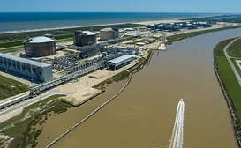 An LNG train is shown bordering a brown waterway