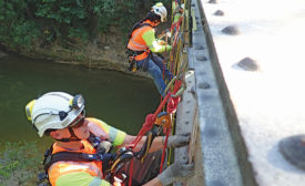 construction workers in safety harnesses on a bridge