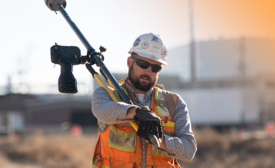 construction worker carrying a camera and tripod
