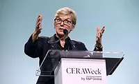 Jennifer Granholm Energy Secretary Jennifer Granholm wearing a black top stands in front of a podium with a clear top. The text on the podium says "CERAWeek by S&P Global"