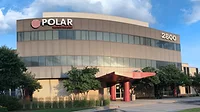 Polar Semiconductor Minnesota A building with a red entrance and two strips of windows running horizontally across with the Polar logo on the building's upper left hand corner.