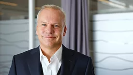 Headshot of Equinor CEO Anders Opedal, smiling and wearing a white button-down and blacks suit