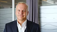 Headshot of Equinor CEO Anders Opedal, smiling and wearing a white button-down and blacks suit