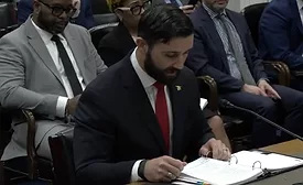 Cameron Hamilton, former acting chief of FEMA, is seated, looking at a binder during congressional testimony