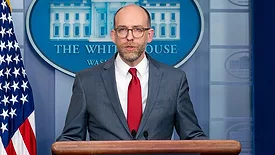 Russel Vought speaks at the podium in the White House briefing room in 2019