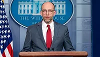 Russel Vought speaks at the podium in the White House briefing room in 2019