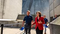 NY Gov Hochul, wearing a red suit jacket and black dress, walks with NY Power Authority members at the Niagara Power Plant