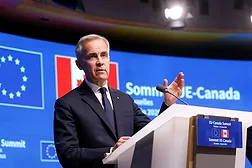 Canada Prime Minister Mark Carney stands at a podium wearing a blue suit