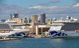 Two cruise ships docked at Port Everglades with Fort Lauderdale skyline in the background, where a $152.2-million bulkhead replacement project is underway