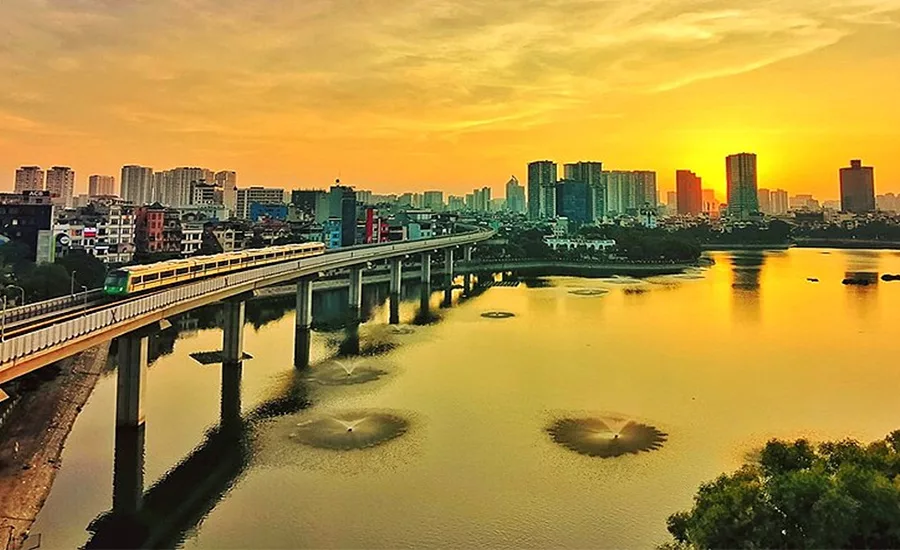 Elevated Hanoi Metro train crossing Hoang Cau Lake at sunset.