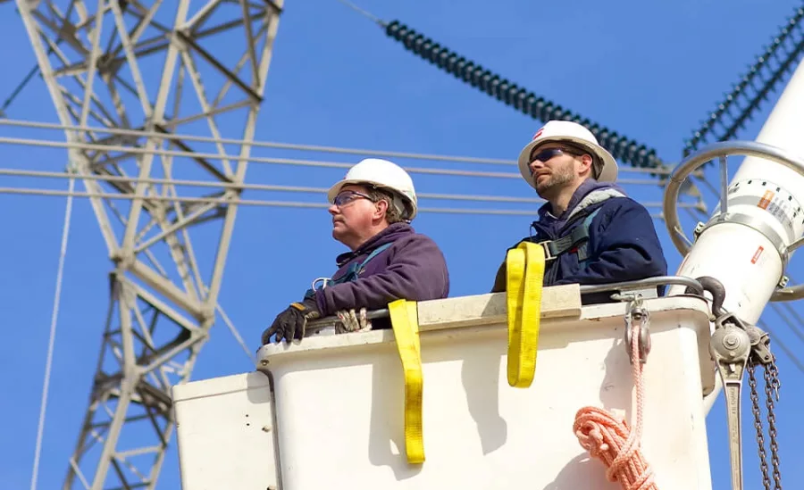 Workers in a cherry picker bucket near transmission lines