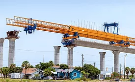 Bridge segment under construction using large orange launching gantry.