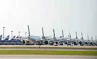 Line of commercial aircraft parked on an airport apron.