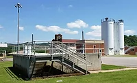Water treatment facility with processing structures, tanks and buildings under clear sky.