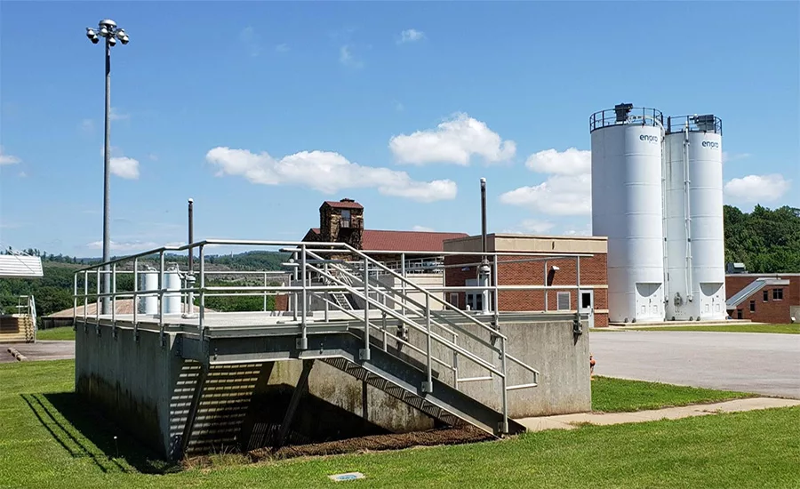 Water treatment facility with processing structures, tanks and buildings under clear sky.