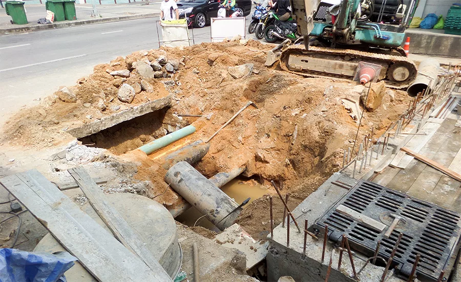Excavation site showing exposed water pipes during a utility line replacement project.