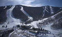 Killington resort A photo of Killington Mountain resort shows a mountain with snowy trails running down and a parking lot and building in the foreground