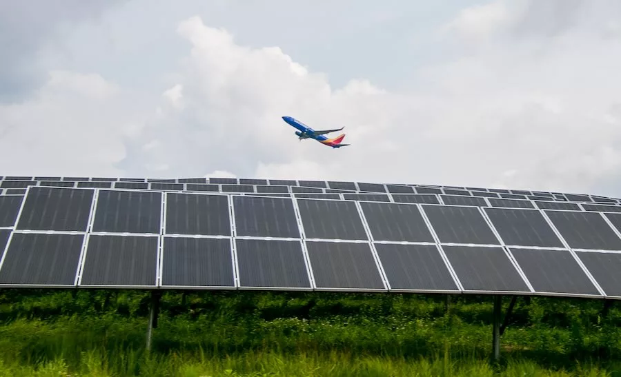 Photo shows an airplane flying over a solar array at the Pittsburgh International Airport