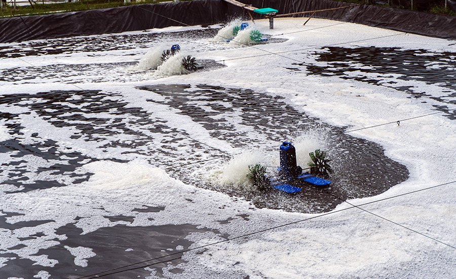 Aeration basins at a wastewater treatment facility, with mechanical mixers circulating water across open treatment cells.