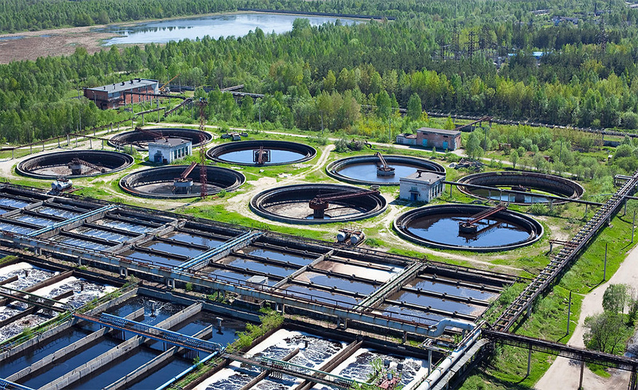 Aerial view of a surface-water treatment facility with circular clarifiers and treatment basins surrounded by vegetated landscape.