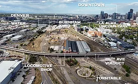 Aerial view of Burnham Yard in Denver with 8th Avenue Viaduct, former rail yard structures and downtown skyline in the distance.