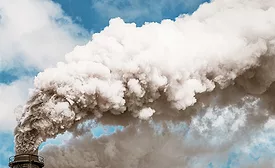 Photo shows a thick plume of smoke from a chimney, stretching across the sky