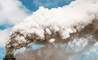 Photo shows a thick plume of smoke from a chimney, stretching across the sky