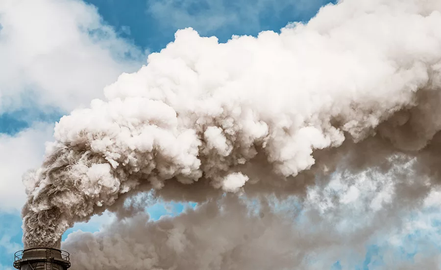 Photo shows a thick plume of smoke from a chimney, stretching across the sky