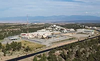 A giant federal nuclear research complex in New Mexico, with a history of WW2 and Cold War bomb component production, faces new state enforcement for delaying radioactive and chemical waste cleanup.