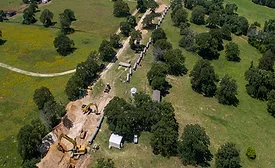 Aerial view of construction crews installing large water transmission pipeline segments along a rural corridor in Central Texas.