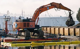 Excavator on barge removing sediment during Lower Duwamish Waterway Superfund cleanup in Seattle.
