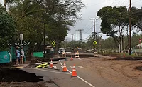 People look over a road damaged by a kona storm on Sunday, March 15, 2026, in Maui County, Hawaii.
