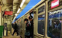CTA train at Howard station in Chicago with riders boarding on platform