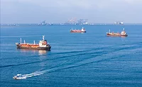 Cost-of-the-War Oil tankers waiting offshore near port cranes
