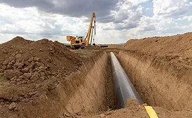 Pipeline installation in an open trench with heavy equipment on site.
