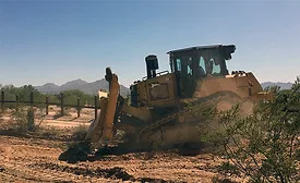 Bulldozer clearing desert terrain during border wall construction in southern Arizona