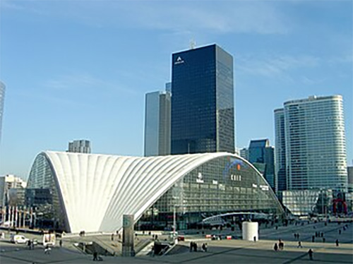 The CNIT showroom in Paris, a large curved shell structure in the La Défense business district surrounded by high-rise office towers.