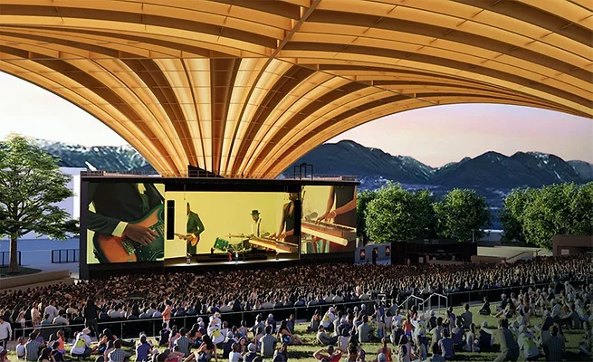 Rendering of Vancouver's Freedom Mobile Arch amphitheater showing a large crowd beneath the sweeping mass-timber roof with mountains visible beyond the stage.