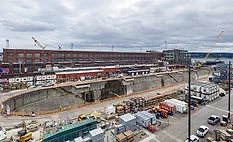 Aerial view of Dry Dock 4 at Puget Sound Naval Shipyard in Bremerton, Wash., with waterfront facilities, construction equipment and support buildings visible.