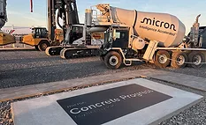 Construction equipment and a commemorative slab marking Micron's July 2026 concrete placement in Clay, N.Y.
